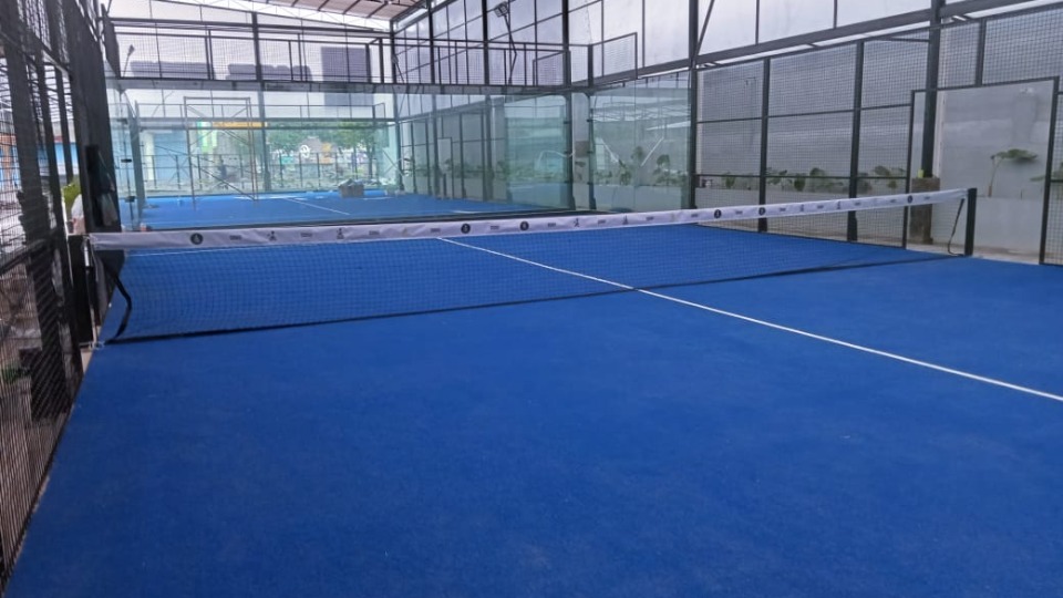 Lapangan Premier Padel dengan kamera siaran dan layar monitor di sisi lapangan