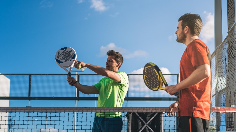 lapangan padel modern di area perkotaan dengan pemain ganda sedang bertanding