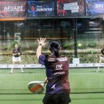 pemain padel memukul bola setelah memantul dari kaca samping