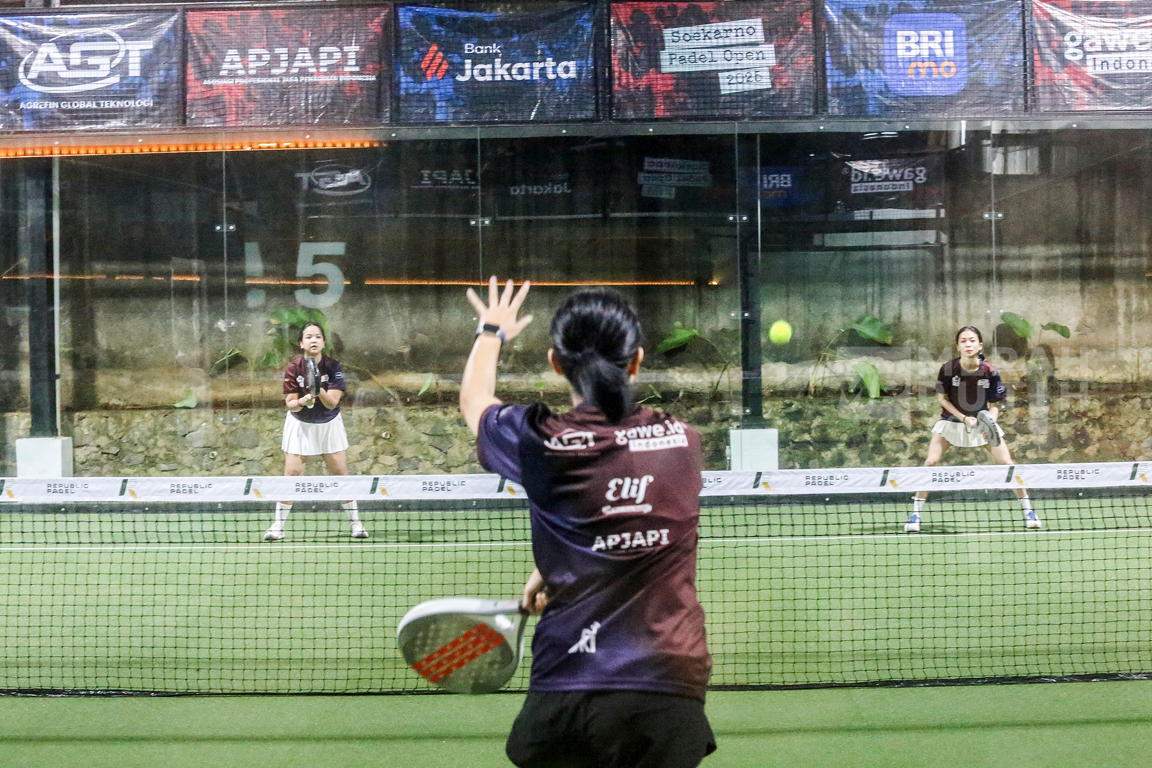 pemain padel memukul bola setelah memantul dari kaca samping